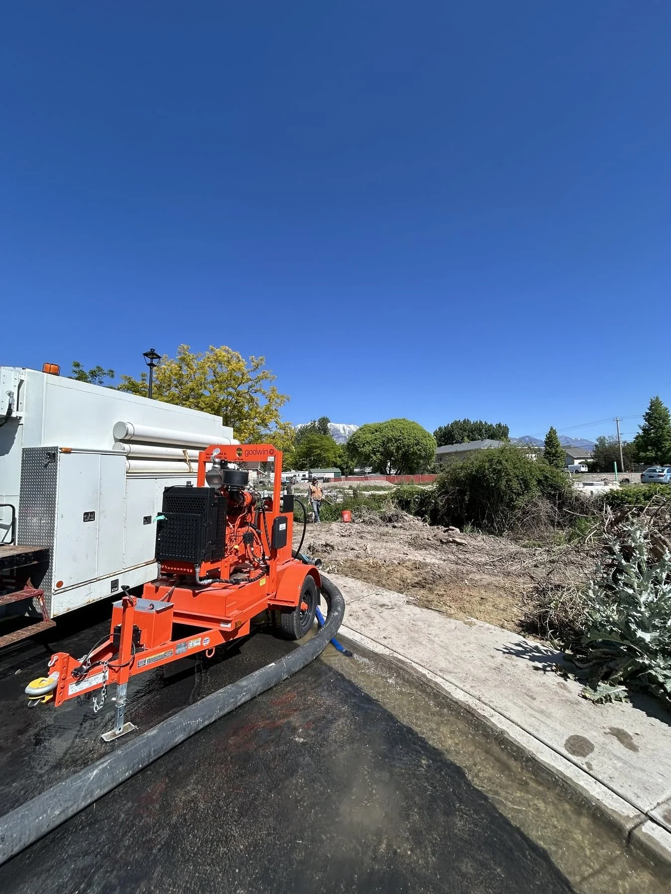 An orange towable dewatering pump set up at a job site to remove water